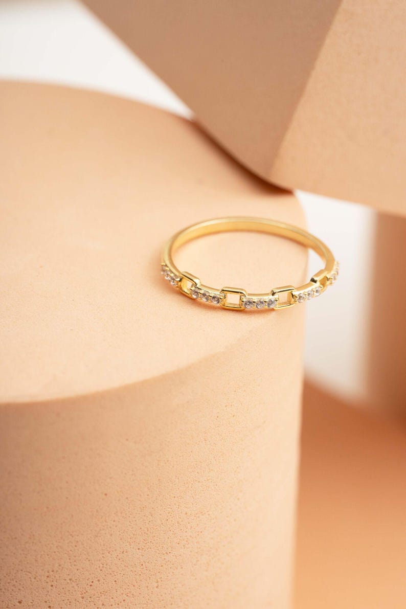 A delicate gold-plated 925 sterling silver chain link band ring encrusted with sparkling clear cubic zirconia stones against a neutral background.