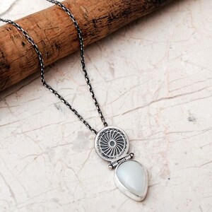Handmade 925 sterling silver teardrop jewelry set featuring a mother of pearl pendant necklace and matching drop earrings adorned with intricate vintage motifs and an oxidized silver finish.