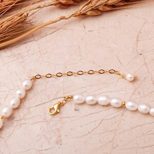 A elegant handmade white pearl strand necklace decorated with gold-plated 925 sterling silver filigree spacers and finished with an adjustable extension chain.