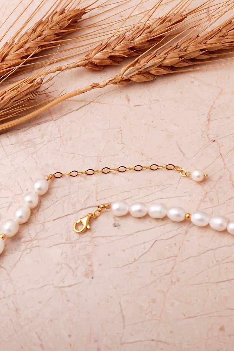 A elegant handmade white pearl strand necklace decorated with gold-plated 925 sterling silver filigree spacers and finished with an adjustable extension chain.