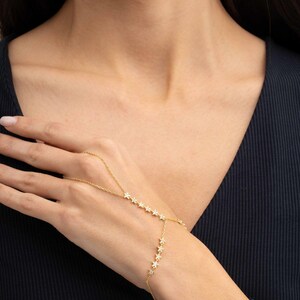 Gold plated 925 sterling silver star hand chain bracelet with sparkling zircon accents connecting from finger to wrist.