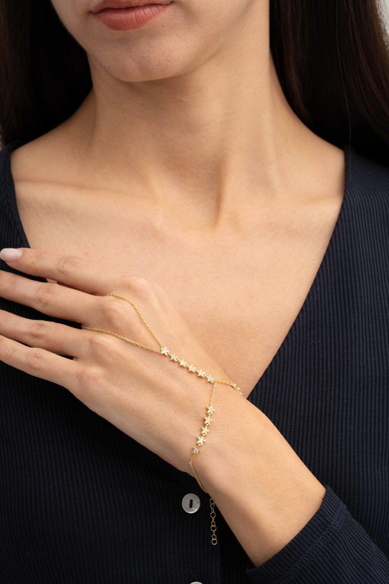 Gold plated 925 sterling silver star hand chain bracelet with sparkling zircon accents connecting from finger to wrist.