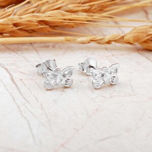 Mini butterfly earrings made of rhodium‑plated sterling silver with a white zircon stone, measuring 6 mm by 9 mm.
