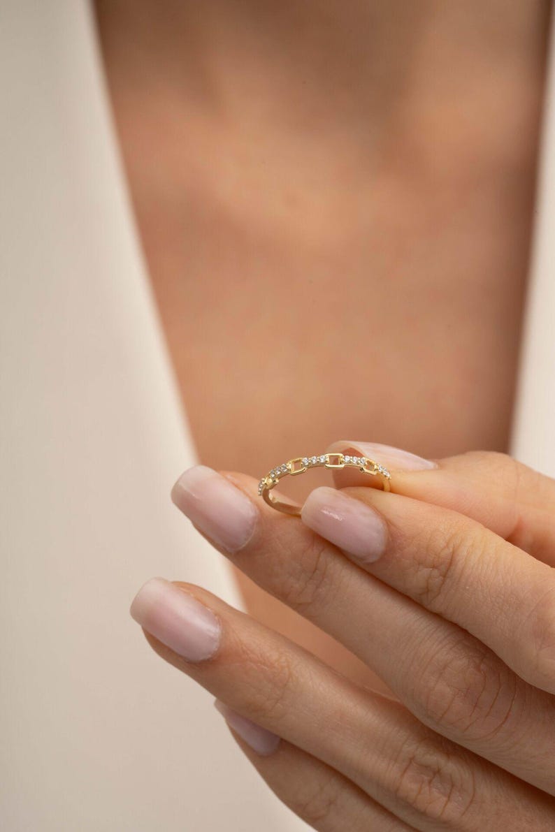 A delicate gold-plated 925 sterling silver chain link band ring encrusted with sparkling clear cubic zirconia stones against a neutral background.