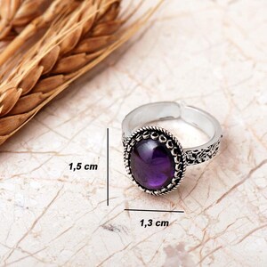 Adjustable oval ring made of 925 sterling silver with a green peridot stone on one side and a purple amethyst stone on the other, showing an oxidized antique finish.