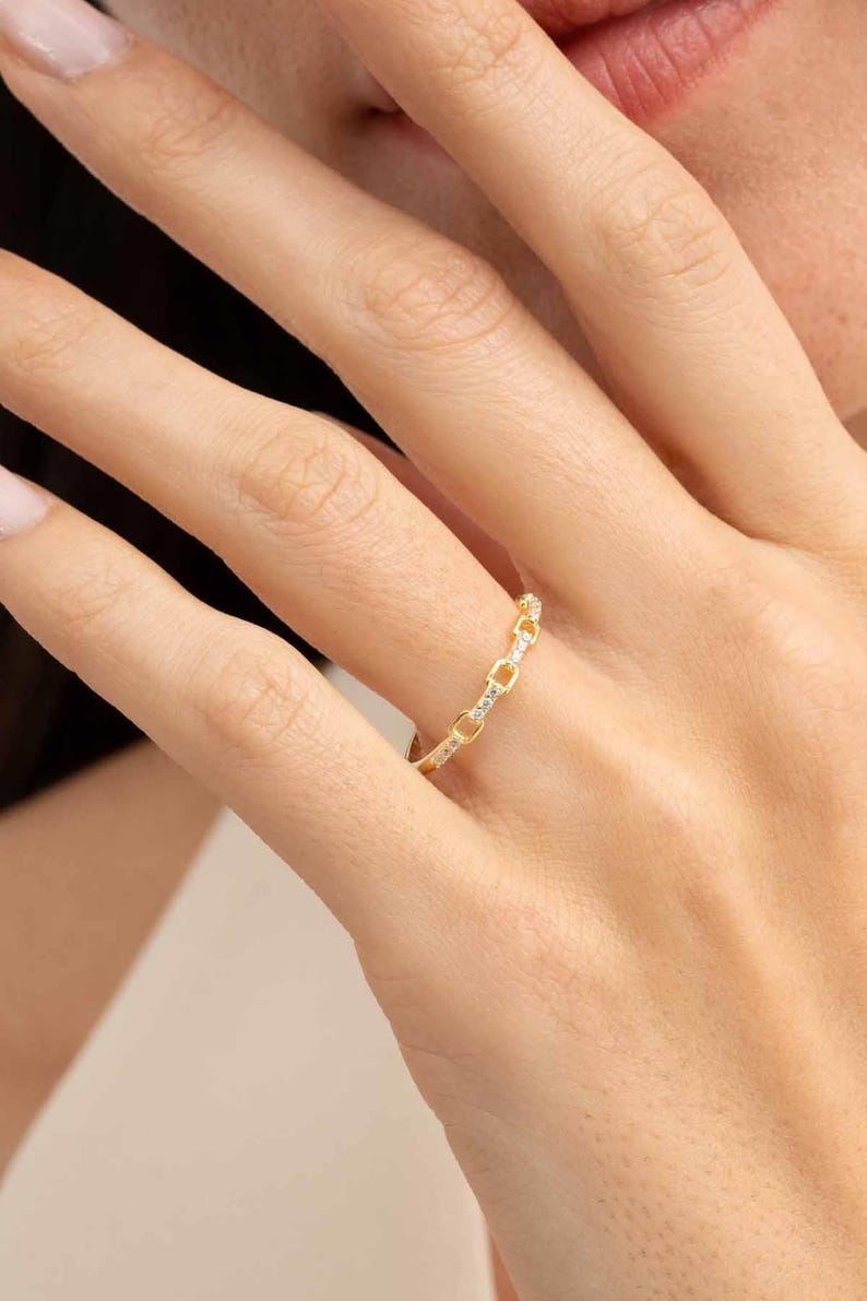 A delicate gold-plated 925 sterling silver chain link band ring encrusted with sparkling clear cubic zirconia stones against a neutral background.