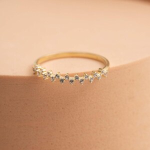 A thin 3mm wide silver ring coated in green gold plating with sparkling clear cubic zirconia stones set around the band.