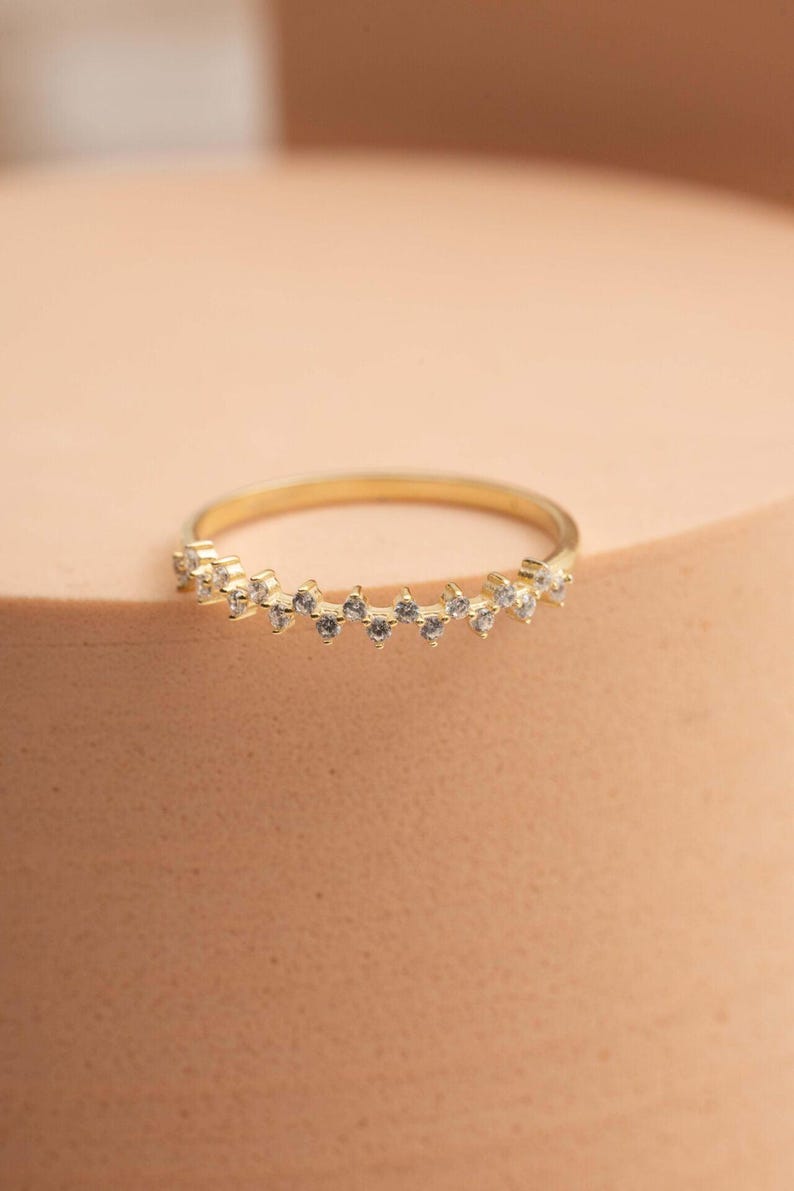 A thin 3mm wide silver ring coated in green gold plating with sparkling clear cubic zirconia stones set around the band.
