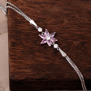 A delicate 925 sterling silver bracelet featuring a centrally placed lotus flower motif set with a brilliant gemstone, attached to a fine chain with an extension link.