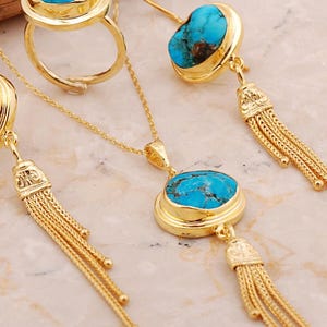 A handmade 925 sterling silver gold plated jewelry set featuring a woven tassel pendant necklace, dangling earrings, and an adjustable ring, all adorned with natural blue turquoise stones.