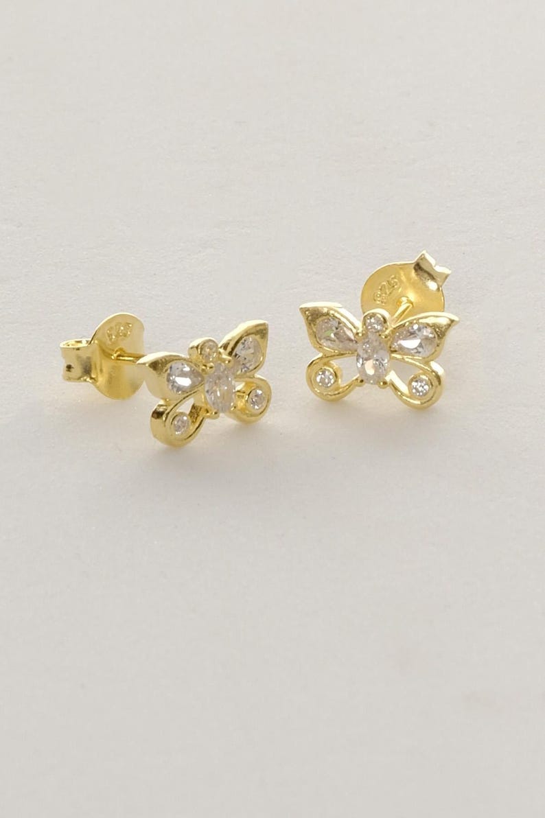 Mini butterfly earrings made of 925 sterling silver with green gold rhodium plating and white zircon stones, measuring 6 mm tall by 9 mm wide.