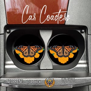 May include: Two black car coasters with a monarch butterfly design. The butterfly has orange and black wings with white spots, set against a black background. The coasters are 2.62 inches in diameter and made of neoprene.