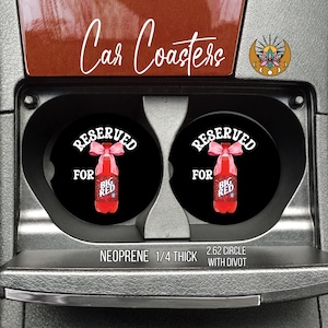 May include: Black car coasters with a red Big Red soda bottle design. The coasters are labeled "Reserved for Big Red" in white text. The text "Car Coasters" is written in cursive. The coasters are 2.62 inches in diameter.