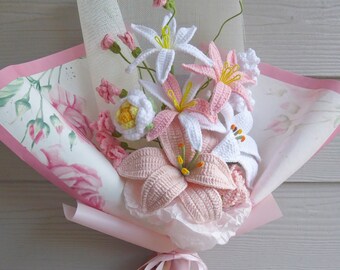 Könnte beinhalten: Ein Strauß gehäkelter Lilien in Rosa und Weiß, verpackt in rosa Seidenpapier und mit einem rosa Band gebunden.