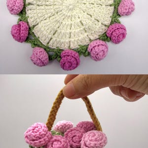 May include: A circular off-white crochet doily featuring a border of green leaves and small pink rose blossoms. Below, a small brown crochet basket with a handle is filled with several pink crocheted rose blossoms and green leaves.