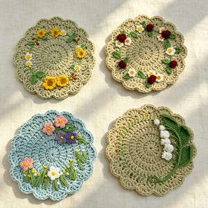 Puede incluir: Cuatro posavasos redondos de ganchillo con bordes festoneados. Dos son de color verde salvia con coronas de flores amarillas o flores rojas y blancas. Uno es azul claro con flores rosas y moradas. Uno es verde salvia con lirios del valle.