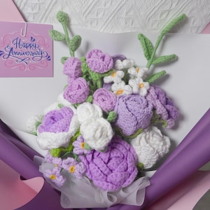 May include: A crocheted bouquet of purple and white flowers with green stems, wrapped in purple and pink tissue paper. The bouquet includes a card that says "Happy Anniversary".
