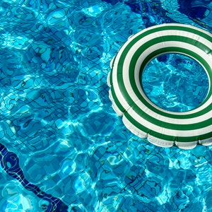 May include: A white and green striped inflatable ring floating in a blue swimming pool.