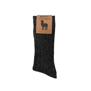 May include: A dark charcoal gray ribbed knit sock with a brown paper label attached at the top. The label features the text "gorux ALPAKA" above a black alpaca silhouette graphic, with size markings "EU 43-46" and "US 10-12" printed below.