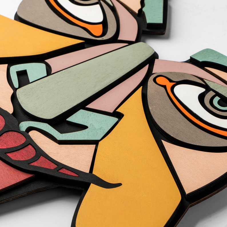 May include: A colorful abstract wall art piece with a butterfly design. The butterfly is made of wood and painted in shades of orange, yellow, green, red, and brown.