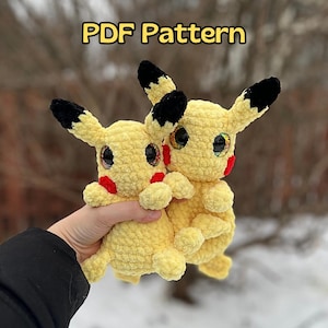 Può includere: Due peluche Pikachu gialli all'uncinetto con orecchie e occhi neri. I peluche hanno guance rosse e si tengono l'un l'altro. Il testo "PDF Pattern" è visibile nella parte superiore dell'immagine.