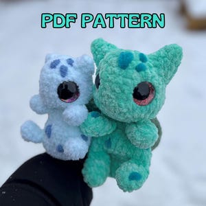 May include: Two plush, handmade creatures. One is light blue with darker blue spots, the other is teal with darker teal spots. Both have large, shiny black eyes with pink accents. The text "PDF PATTERN" is at the top.