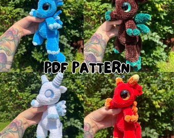 May include: Four crocheted dragon toys in blue, brown, white, and red. Each dragon has unique features, including horns, wings, and different color accents. The text "PDF PATTERN" is displayed across the image.