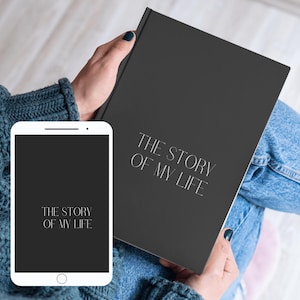 Puede incluir: Una persona sosteniendo un diario negro con el texto "The Story of My Life" en la portada. La persona también sostiene un teléfono inteligente negro con el mismo texto en la pantalla.