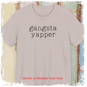 May include: A light grey t-shirt with the text "gangsta yapper" printed in black.