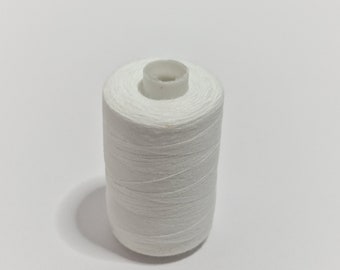 May include: A white cotton thread spool, tightly wound around a white plastic core. The thread is a bright white colour, and the spool is cylindrical. The image is taken against a plain white background.