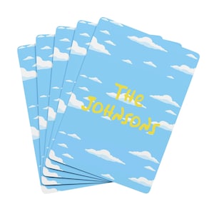 May include: A stack of five light blue cards with a sky and cloud design. The cards have the text "The Johnsons" in yellow. The cards are arranged in a fanned-out pattern.