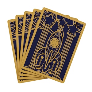 May include: A deck of playing cards with a navy blue background and gold art deco style illustrations. The cards feature a rocket ship, stars, and the initials "CT". The edges of the cards are gold.