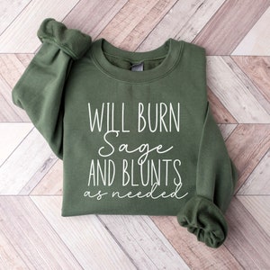 May include: A green sweatshirt with the text "Will Burn Sage and Blunts as needed" printed in white.