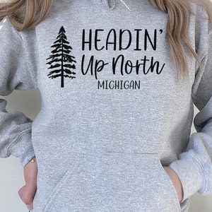 May include: Gray hooded sweatshirt with a black print of a pine tree and the text "Headin' Up North Michigan".