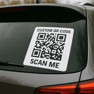 May include: A white rectangular sticker with a black QR code and the text "CUSTOM QR CODE" above and "SCAN ME" below. The sticker is affixed to the rear window of a gray car.