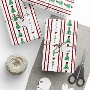 May include: Wrapped gifts with festive Christmas-themed paper. The white paper features red vertical stripes with the word "NOEL", hearts, and green Christmas trees. Each gift is tied with twine and a white tag. A ball of twine and scissors are also visible.