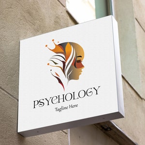 May include: A white sign with a logo for a psychology practice. The logo features a stylized image of a person's face with a crown and floral design. The text "Psychology" is written in a black serif font below the logo. The tagline "Tagline Here" is written in a smaller font below the text "Psychology".