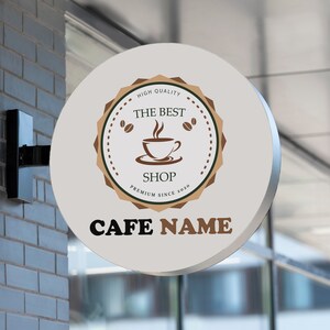 May include: White round sign with brown text and a logo of a coffee cup with steam. The text reads "High Quality, The Best Shop, Premium Since 2020, CAFE NAME".