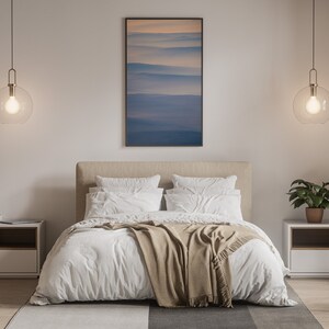 May include: A modern bedroom with a neutral color palette. The bed has white bedding and a tan throw blanket. Two bedside tables with lamps hang from the ceiling. A framed landscape art piece hangs above the bed. A potted plant sits on one of the bedside tables.