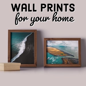 May include: Two framed photographs of aerial landscapes. The first photo shows a black sand beach with a white wave crashing on the shore. The second photo shows a coastline with a river flowing through a field of yellow grass. The text "WALL PRINTS for your home" is at the top of the image.