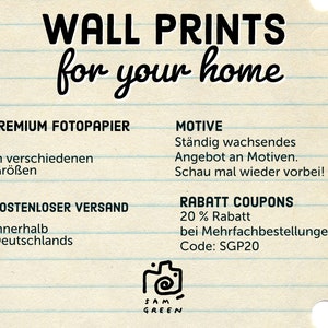 May include: A white sheet of paper with black text that reads "WALL PRINTS for your home". The text is in a handwritten style. Below the text are details about the product, including premium photo paper, free shipping within Germany, and a discount code for multiple orders. The text also includes the phrase "St&auml;ndig wachsendes Angebot an Motiven. Schau mal wieder vorbei!" which translates to "Constantly growing selection of motifs. Check back again!"
