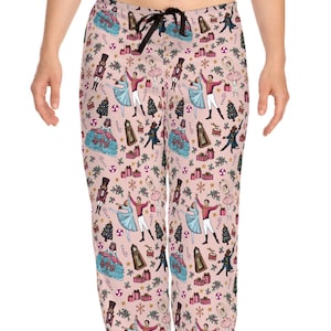 May include: Pink pajama pants with a repeating pattern of ballet dancers, Christmas trees, wrapped gifts, and nutcrackers. The pants have a drawstring waist and a relaxed fit.