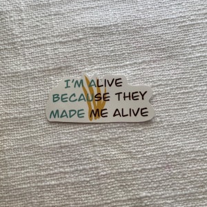 May include: White sticker with a cloud shape and the text "I'm alive because they made me alive" in blue and brown lettering.