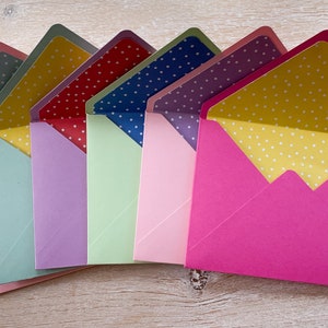 May include: A set of seven envelopes with white polka dots on the inside flap. The envelopes are in various colors: pink, green, purple, light green, pink, purple, and hot pink.