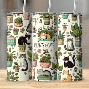 Op de afbeelding: Een witte roestvrijstalen tumbler met een kleurrijk patroon van potplanten en katten. De tumbler heeft een deksel en een rietje. De tekst "Plants & Cats" is op de tumbler gedrukt.