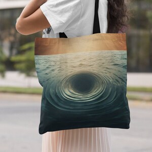 Può includere: Una borsa tote in tela nera con un design a vortice oceanico vorticoso con un centro scuro. Lo sfondo è di colore arancione e giallo sbiadito.