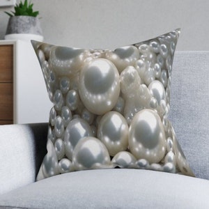 May include: A white throw pillow with a close-up image of a pile of white pearls.