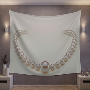 May include: A white tapestry with a pearl necklace draped across it. The pearls are large and round, and they are arranged in a simple, elegant design.