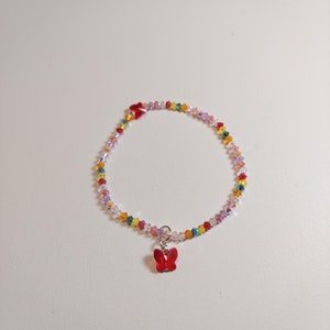 May include: A delicate bracelet made of colorful crystal beads with a red butterfly charm.