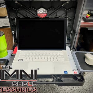 May include: Black Omni Shelf accessories with a white laptop, mouse, and a green tumbler. The shelf has a cup holder and a mouse pad. The text "THE OMNI SHELF ACCESSORIES" is visible.